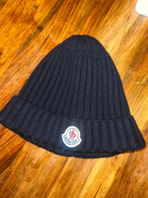 Moncler mössa - Äkta marinblå mössa från Moncler, köpt från NK. Kvitto medföljer. Använd bara några gånger, nästan helt ny. 