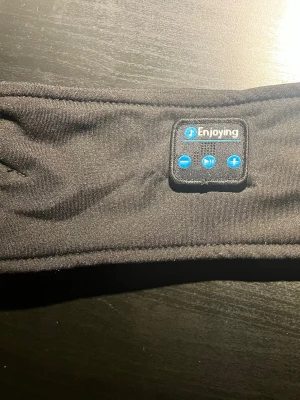 Pannband med inbyggda hörlurar  - Svart pannband med inbyggda hörlurar. HELT NYA. Funkar bra att ha när man sover eller springer. 😴🏃‍♂️‍➡️Dessa är även populära att använda under skidhjälmen. Så du kan lyssna på musik i skidbacken! ⛷️🏂 De har Bluetooth. USB-C kabel medföljer. Pannbandet är svart som på bilden även om kartongen visar ett grått band. 🙌🙌 Bara att höra av er vid frågor! 🤝