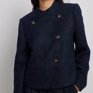 Mörkblå blazer från Claire Rose x Na-kd - Snygg mörkblå kavaj från Claire Rose med asymmetrisk knäppning. Perfekt för dig som vill ha något stilrent och trendigt 🔥 den är använd, finns knottra på ärmarna men enkelt att tabort. Säljer då den inte kommer till användning längre 💕