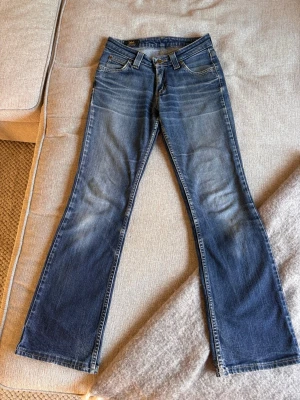 Blå bootcut jeans från Lee - Snygga blå bootcut jeans från Lee. Jeansen har låg midja, dragkedja och knapp med Lee-logga. Storleken står inte men jag skulle säga att det passar en XS och någon som är 155-165