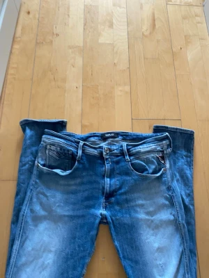 Blå jeans från Replay - Snygga blå jeans från Replay med klassisk femficksdesign och diskreta slitningar. Jeansen har normal passform och är tillverkade i bomull med en skön stretch. Perfekta för dig som gillar en avslappnad men stilren look.
