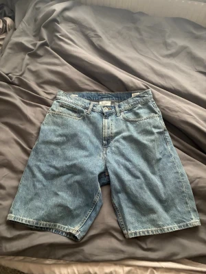 Blå jorts från Vailent - Klassiska blå jeansshorts från Vailent med fem fickor och normal passform. Shortsen har en rak modell och är tillverkade i slitstark bomull. Perfekta för sommardagar och enkla att matcha med olika stilar.