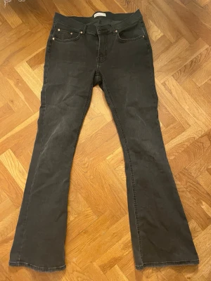 Svarta bootcut jeans med medel/låg midja - Säljer ett par svarta bootcut jeans med medel/låg midja och klassiska fickor. Jeansen är stretchiga och är svart gråa. Aldrig använda. 