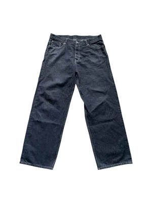 Weekday Jeans - Snygga svarta jeans med rak passform och klassisk femficksdesign från Weekday. Jeansen har normal midja och är tillverkade i denim med tydliga sömmar. Perfekta för en avslappnad och trendig look. FYI: Dom har små små vita färg fläckar nertill (se bild). Passa på att fråga om bild eller mått om det behövs! ⭐️