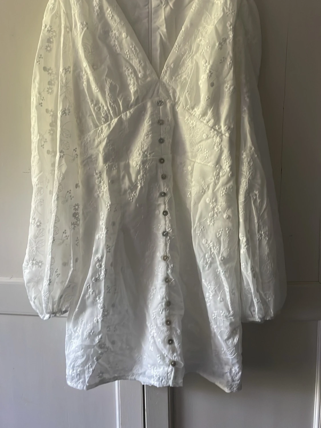 Vit broderad kortklänning med knappar och lång puffärm. Stl M
