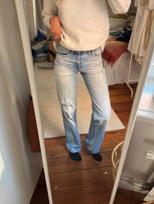 Ljusblå bootcut jeans med slitningar - Säljer dessa Zara jeans som är helt oanvända, köpte på Zara i Italien och har inte fått användning av de alls tyvärr. De är ett ett par ljusblå utsvängda jeans med snygga slitningar på låret och vid fickan. Jeansen har klassisk femficksmodell, låg midja och är tillverkade i mjuk denim. Perfekta för en avslappnad och trendig look. 🩷