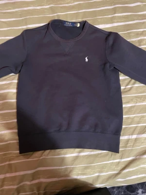 Svart sweatshirt från Polo Ralph Lauren - Klassisk svart sweatshirt från Polo Ralph Lauren med den ikoniska vita logobrodyrn på bröstet. Väldigt fräsch och clean sweatshirt. Använd ett par gånger under speciella tillfällen. Storleken är S. Priset är 250 men går självklart att diskutera mer vid en snabbaffär, om du vill se fler bilder så är det bara att hojta till!