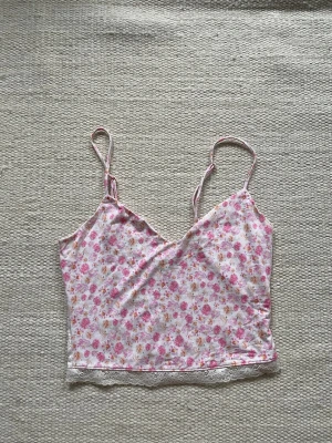 Blommig linnetopp från Victoria's Secret - Söt linnetopp från Victoria's Secret med blommigt mönster. Toppen har tunna axelband, v-ringning och spetsdetalj längst ner & på ryggen. Perfekt för sommaren. Ingen storlek men förmodlingen S/M