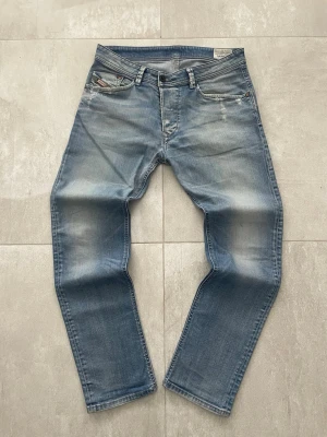 Ljusblå jeans från Diesel - Säljer ett par ljusblå jeans från Diesel med klassisk femficksdesign och diskreta slitningar. Jeansen har raka ben och en avslappnad passform. Materialet är mjukt denim i bomull och har snygga detaljer vid fickorna.
