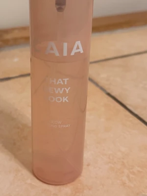 CAIA  That Dewy Look Glow Setting Spray - Fräsch face mist från Caia i en snygg ljusrosa plastflaska. Produkten heter 'That Dewy Look Glow Setting Spray' och ger huden en återfuktad, glowig finish. Perfekt för dig som vill ha en naturlig lyster och fräsch känsla hela dagen.