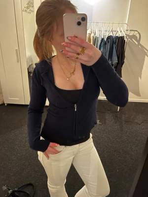 Mörkblå hoodie från Gina Tricot - Säljer en mörkblå hoodie från Gina Tricot med dragkedja framtill och huva. Tröjan är croppad och har långa ärmar. Inga defekter använt fåtal gånger.