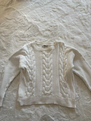 Vit kabelstickad tröja  - Kabelstickad vit tröja med rund halsringning och ribbade muddar i storlek 158/164, mycket fint skick. 