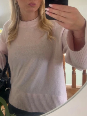 Ljusrosa stickad tröja - Mysig ljusrosa stickad tröja med rund halsringning och ribbade muddar vid ärmslut och nederkant. Tröjan har en avslappnad passform och är perfekt för att hålla värmen under kyliga dagar. Passar till både jeans och kjol. Strl 146-152 passar xs-xs