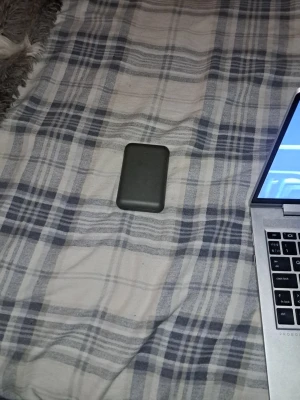 Svart powerbank med LED-indikator - Säljer en kompakt svart powerbank med rundade hörn och en tydlig blå LED-indikator på framsidan. Perfekt att ha med sig för att ladda mobilen när du är på språng. Smidig storlek som enkelt får plats i fickan eller väskan.