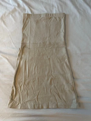 Beige klänning från Djerf Avenue - Säljer en enkel och stilren beige kjol från Djerf Avenue i storlek XS. Kjolen har en rak passform och är tillverkad i ett mjukt bomullsmaterial. Perfekt att matcha med en crop top eller stickad tröja för en avslappnad look.