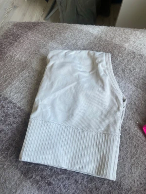 Ljusgrå ribbad body - Säljer en ljusgrå body med ribbad nederkant och brottarrygg. Materialet är mjukt och stretchigt, perfekt för en bekväm känsla. Passar bra under kläder eller som ett snyggt basplagg. Inget synligt märke.