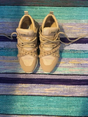 Beige sneakers från NLY Shoes - Snygga beige sneakers från NLY Shoes med coola nitar och detaljerade band över foten. Skorna har en chunky vit sula, meshpartier och snörning framtill. Perfekta för dig som vill sticka ut med din stil.