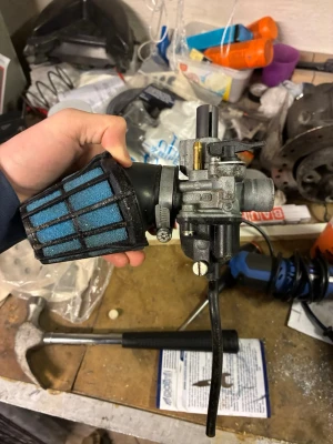 Förgasare med blått sportluftfilter - Säljer en förgasare med ett blått sportluftfilter, perfekt för moppe eller scooter. Luftfiltret har ett svart plastgaller och förgasaren är i metall med flera anslutningar och justerskruvar. Passar dig som vill trimma eller serva ditt fordon.