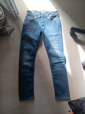 HELT NYA! Blå jack and Jones jeans modell slim/Glenn. - Säljer ett par HELT NYA blå jeans från j&j med design på bakfickan. Säljer pga fel passform. Storlek 29/32. Prislapp kvar