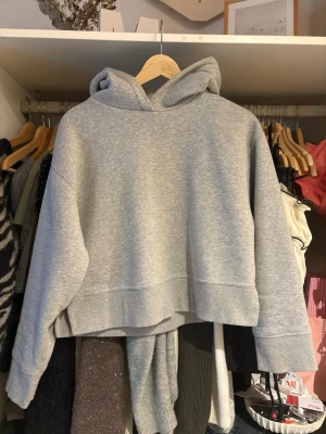 Zara hoodie  - Snygg grå croppad hoodie med huva och breda muddar. Hoodien har en avslappnad passform och är tillverkad i mjukt sweatshirtmaterial. Perfekt för en chill och trendig look.