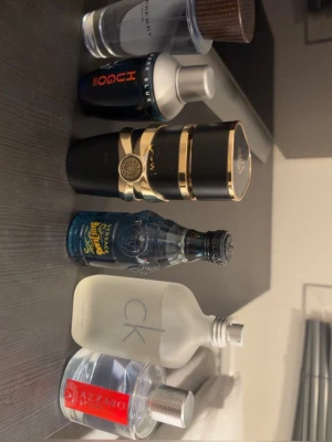 Mix av herrparfymer från kända märken - Samling med flera herrparfymer från märken som Hugo Boss, Versace Blue Jeans, Calvin Klein, Paco Rabanne och fler. Flakongerna är i olika färger och former, från blått och svart till frostat glas och guldiga detaljer. Perfekt för dig som vill testa olika dofter.