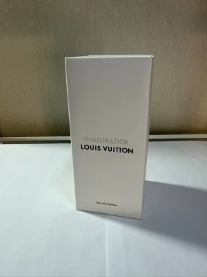 Louis Vuitton Imagination parfym - Louis Vuitton Imagination Eau de Parfum i elegant vit kartong. Parfymen kommer i en stilren, rektangulär förpackning med minimalistisk design och svart text. Perfekt för dig som gillar exklusiva dofter och lyxiga märken.