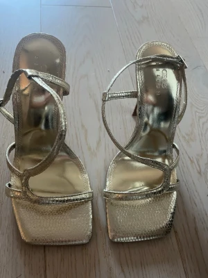 Guldiga klackaskor - Guldiga klackaskor i väldigt bra skick. Strl - 38. Från Asos design. 