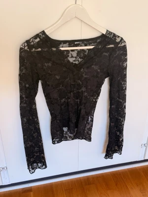 Svart spetsblus från Gina Tricot - Säljer en svart långärmad spetsblus från Gina Tricot. Blusen har v-ringning och är helt i genomskinlig spets med blommigt mönster. Perfekt för dig som vill ha en snygg och trendig topp med extra detaljer.