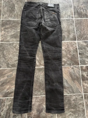  Nudie jeans svarta  - Säljer ett par svarta slim fit jeans från Nudie. 30/34 Dåligt skick då baksidan är lagad och skrevet är de hål i hör av dig vid frågor 