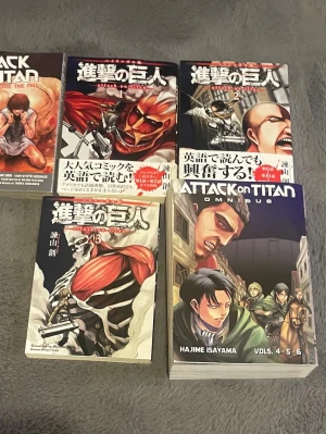 Attack on Titan manga samling - Samling av manga-böcker från serien Attack on Titan av Hajime Isayama. Omslagen har starka färger med illustrationer av karaktärer och titaner. Böckerna är i pocketformat och har både japansk och engelsk text på omslagen. Perfekt för manga-fans och samlare. Har engelsk språk i texten