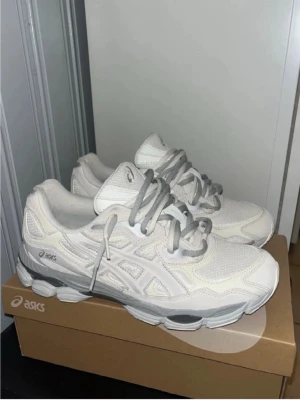 Asics sneakers cream/cloud grey - Snygga cream sneakers från Asics med detaljer i mesh och skinn. Skorna har en chunky sula och  skosnören som ger en sportig vibe. Perfekta för dig som gillar stilrena och bekväma sneakers till vardags. Klassisk Asics-logga på sidan.