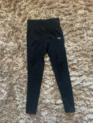 Svarta leggings från ICANIWILL - Svarta leggings med hög midja från ICANIWILL. Tight passform och stretchigt material som sitter skönt på kroppen. Diskret logga på ena höften. Perfekta för träning eller chill dagar.