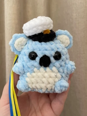 Handvirkat studenthänge – blå koala med studentmössa - Handvirkad koala i ljusblått med studentmössa och blågult band. En unik och personlig studentpresent som sticker ut och håller länge. Mjuk, lätt och perfekt att bära under studentdagen. Ett fint minne att spara efter studenten.