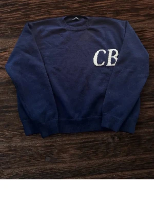 Mörkblå stickad tröja Cole Buxton - Fin marinblå sweatshirt från Cole Buxton i 100% bomull. Vit broderad CB-logga på bröstet. Använd men i nyskick. Mjuk och tjock kvalitet och tillverkad i England. Storlek Medium. Pris: 499 kr Skriv om du vill ha fler bilder! 