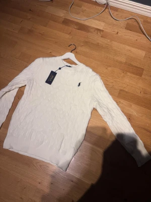 Vit kabelstickad tröja Polo Ralph Lauren - Kabelstickad vit tröja från Polo Ralph Lauren, riktigt snygg och stilren tröja, perfekt för kyliga sommarkvällar, riktigt skönt material