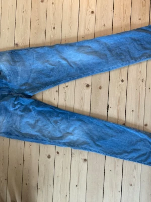 Blå jeans från Replay, modell Anbass - Snygga blå jeans från Replay, modell Anbass. De har en klassisk femficksdesign, normal midja och raka ben. Jeansen är i mjukt denimtyg med lätt slitna detaljer och Replay-logga på fickan. Perfekta för en avslappnad och trendig stil.