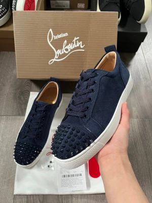 Marinblå Christian Louboutin sneakers - Snygga marinblå sneakers från Christian Louboutin med klassiska nitar på tån och vit sula🤩 Storlek 40, Allt på bild följs med🙌🏻 Hör av er funderingar, pris ej hugget i sten😇