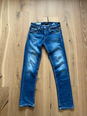 Blå slim fit  jeans från replay  - Säljer ett par blå slim fit jeans från replay Jeans med klassisk femficksmodell och snygga slitningar framtill. Jeansen har normal midja, dragkedjegylf och kontrastsömmar. Perfekta för en avslappnad och trendig stil. Finns en liten defekt på höger lår men inget som märks så mycket 