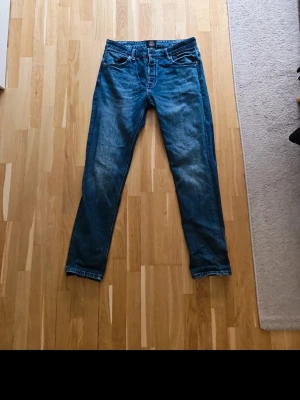 Jeans från Neuw - Säljer ett par blå slim fit jeans med snygga slitningar och tvättade detaljer på benen. Klassisk femficksmodell med normal midja och dragkedja. Perfekta för en avslappnad och trendig look.