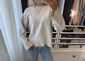 Beige stickad tröja med rund hals - Mysig beige stickad tröja med rund hals och långa ärmar. Tröjan har breda ribbstickade muddar vid ärmslut och nederkant. Perfekt att matcha med jeans för en avslappnad look.