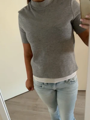 Grå polo topp kortärmad - En stilren grå topp med polo hals, lite sliten och lite trådar som hänger men det går ju att fixa eller klippa av!