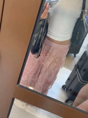 Rosa långkjol i spets - Säljer en romantisk rosa långkjol med volangdetaljer och spetsmaterial. Kjolen har en elastisk midja och ett luftigt fall som ger en bohemisk känsla. Perfekt för dig som vill ha en söt och feminin look.