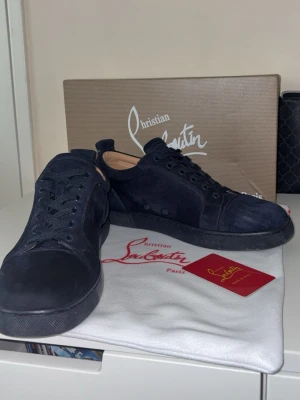 Christian Louboutin Navy - Christian Louboutin sneakers i marinblå mocka med den ikoniska röda sulan. Originalkartong och dustbag ingår.  ⭐️ Skick: 7.5/10 (Lätt använda, mindre slitage på sulorna) 🎨 Färg: Marinblå 📦 Snabb och noggrann frakt