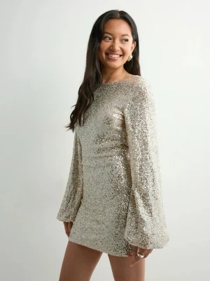 Glittrig kortklänning med öppen rygg - Säljer en glittrig kortklänning i champagnefärg med långa vida ärmar och snygg öppen rygg. Klänningen har en figurnära passform och är täckt av paljetter som ger ett riktigt statement-utseende. Perfekt för dig som vill sticka ut på nästa fest!