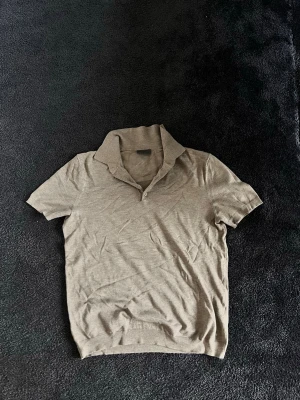 Beige kortärmad skjorta med krage - Säljer en stilren beige skjorta med korta ärmar och klassisk krage ifrån H&M . Skjortan har två knappar framtill och är gjord i ett mjukt material som känns skönt mot huden. Perfekt för dig som gillar en enkel och clean look.