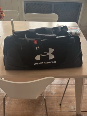 Under Armour Duffel Bag - Säljer denna väska då den är lite för stor för min smak. Jag har aldrig använt den men jag har bara glömt att skicka tillbaka under tidsperioden man hade på sig. Skriv om ni har frågor!!🙌🙌🙌