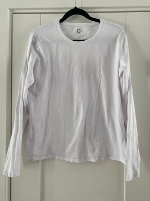 Vit långärmad topp i bomull - En basic vit långärmad topp med rund halsringning. Tillverkad i mjuk bomull, perfekt att styla lager på lager eller bära som den är. Enkel och clean design utan detaljer eller mönster. Sparsamt använd och i fint begagnat skick   Mått Över bröstet: ca 52 cm Längd från axeln och ner: ca 59 cm  95% bomull och 5% elastan  Kommer från ett djur och rökfritt hem