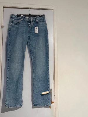 Blå raka jeans  - Säljer ett par klassiska blå raka jeans  med knappgylf och fickor. Jeansen har en tidlös tvätt och är gjorda i 100% bomull för en skön och avslappnad look. Perfekta till sneakers eller boots för en chill stil. Aldrig använda helt nya 