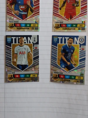 AdrenalynXL Panini FIFA 365 samlarkort TITAN och Dominator - Samling med fyra FIFA 365 samlarkort med fotbollsspelare, inklusive TITAN och DOMINATOR-serierna. Kort i färgerna blå, röd, vit och guld med holografiska detaljer och spelarnas namn, klubb och statistik tryckt på framsidan. Perfekt för dig som gillar fotboll och samlarkort.