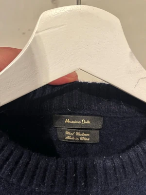 Mörkblå stickad tröja Massimo Dutti - Klassisk mörkblå stickad tröja från Massimo Dutti i en mjuk ull- och kashmirblandning. Tröjan har rund halsringning och långa ärmar, perfekt för kyliga dagar. Enkel och stilren design som passar till det mesta.